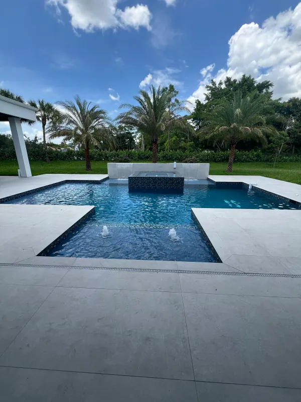 Geometric pool with a raised spa, sun-shelf bubblers and a wide porcelain deck