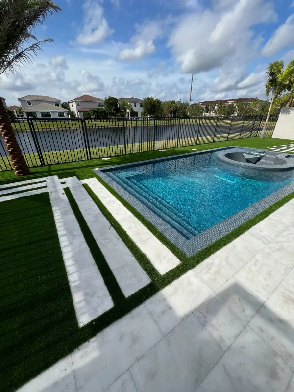 Modern pool with iridescent glass-tile steps and a round in-pool fire bowl by a lake